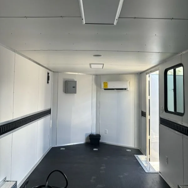 Finished interior of an enclosed trailer with AC unit and bright wall lining