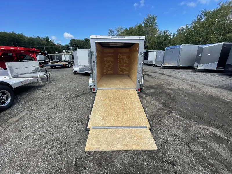 Interior of a small enclosed trailer with plywood flooring and tie-down space